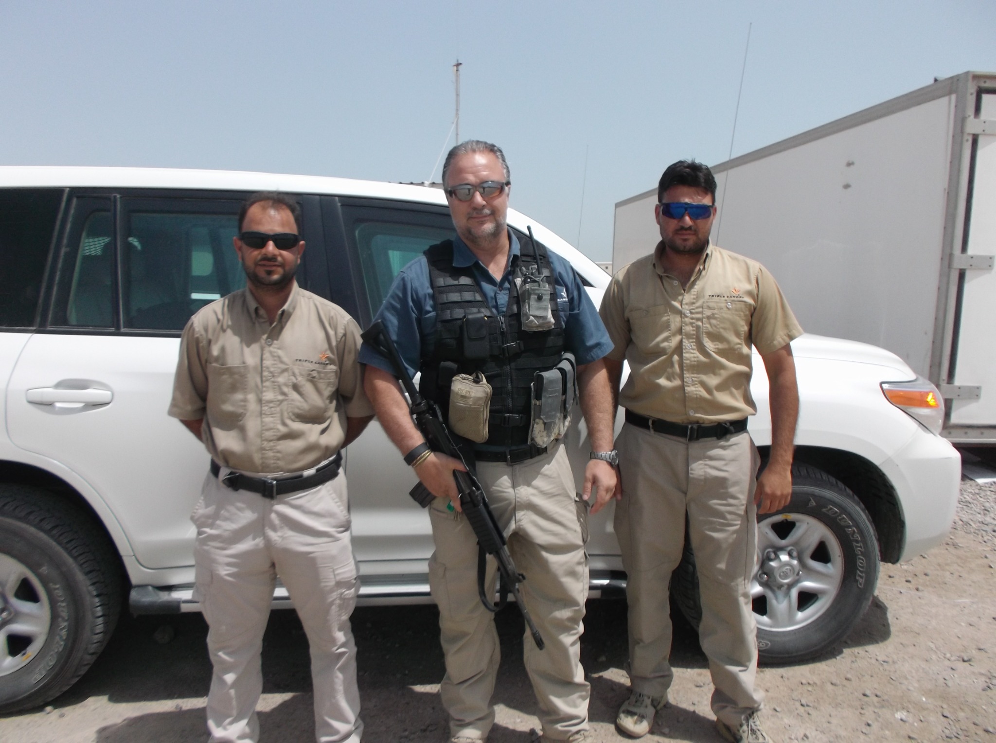 Johan Raath with colleagues beside a vehicle in Iraq